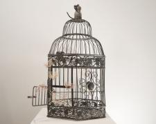"An Escape", 2021, embroidery floss, clear cord, metal bird cage, 10.5 x 14.5 x 19"
