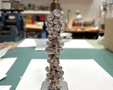 "Dirty Words", 2024, 35 rings: sterling, unknown yellow metal, glass, paper, 7 x 2 x 2"