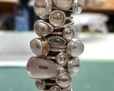 "Dirty Words" (detail), 2024, 35 rings: sterling, unknown yellow metal, glass, paper, 7 x 2 x 2"