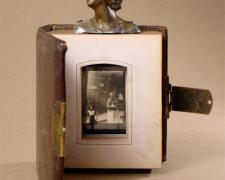 Calcutta 2006 Assemblage - leather bound photo album, head from cast metal figurine, glass lantern slide 9 x 8 x 8"