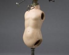 Minutes 2007 Assemblage - doll torso, brass knob, miscellaneous objects, brass stand, steel rods 18 1/2 x 8 x 5 3/4"